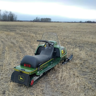 One John Deere Cyclone sled sitting out in a farmer's field. 