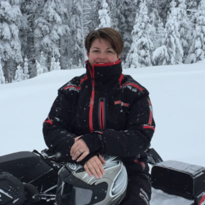 Lady sledder sitting on snowmobile. 