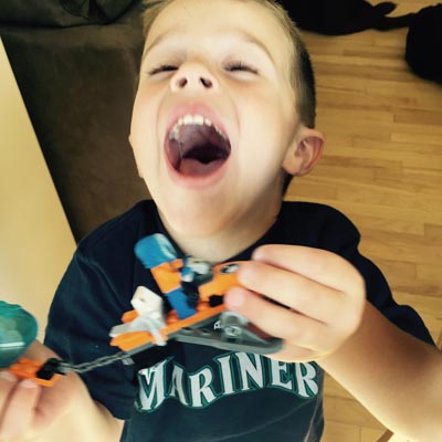 Grayson laughing and holding his LEGO. 