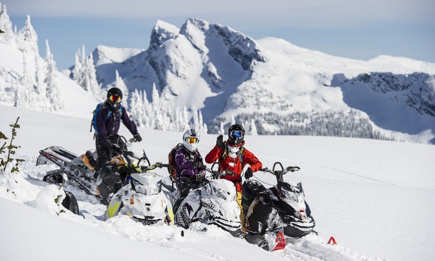 Three snowmobilers pose in the mountains in Revelstoke.