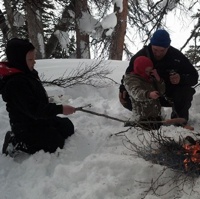 Landon, Broden and Dax Robinson roasting hot dogs over a fire. 