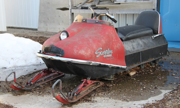 A red vintage Scorpion Trail-A-Sled snowmobile. 