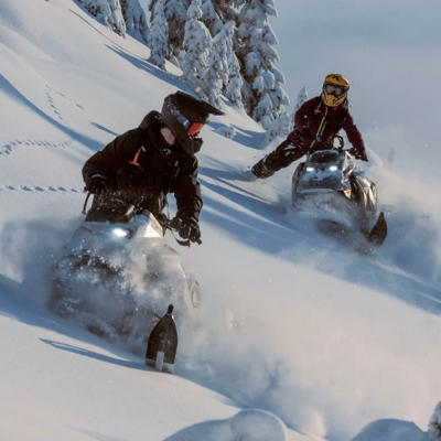 The Ski-Doo logo, above a photo of two snowmobiles riding in deep powder on a hillside, with the bold text 