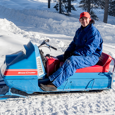 Person sitting on a Snow Cruiser sled. 