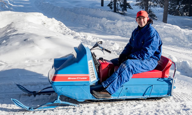 Person sitting on a Snow Cruiser sled. 