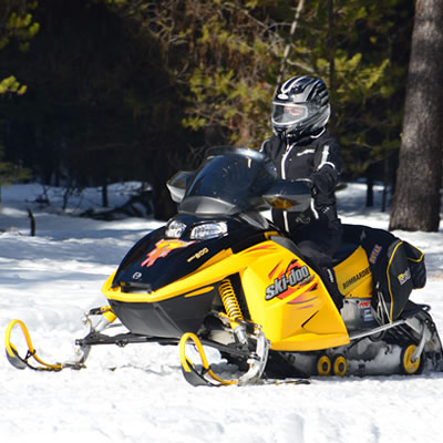 A snowmobiler on a yellow snowmobile. 