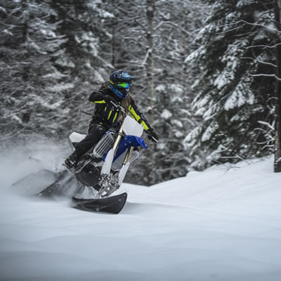 The Timbersled ARO 120 being ridden on a snowy day in the forest. 