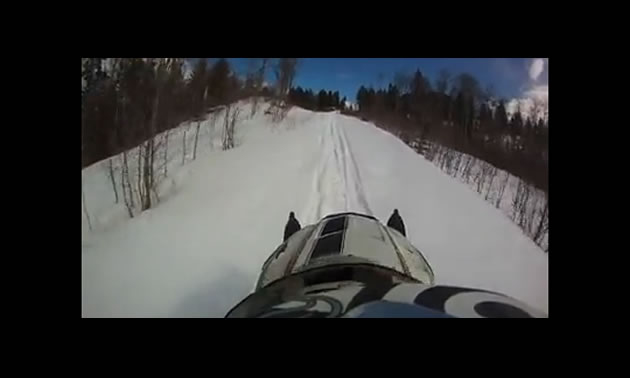A person on a snowmobile riding along a trail. 