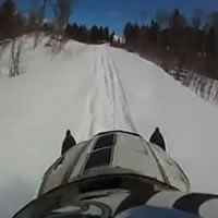 A person on a snowmobile riding along a trail. 
