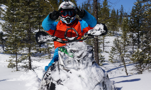 Dargis is riding a snowmobile through trees.