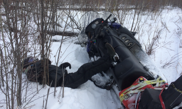 Man fell over on snowmobile. 