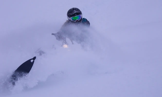 A women laying a sled over in the snow. 