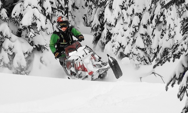 A woman carving through the snow on her snowmobile. 