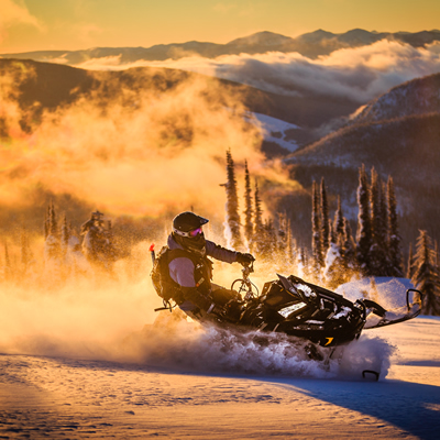 Billy Stevens snowmobiling with the sunset behind him. 