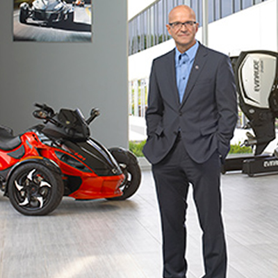 BRP CEO José Boisjoli standing in front of red motorcycle. 