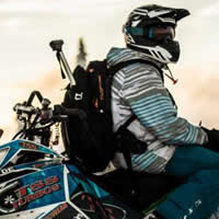 A man sitting backwards on a blue snowmobile. 