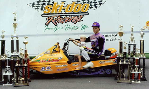 An old photo of Chad sitting with his dad on a sled. 