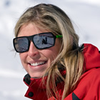 Photo of a blonde haired women wearing shades and a red jacket. 
