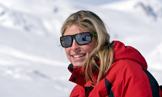 Photo of a blonde haired women wearing shades and a red jacket. 