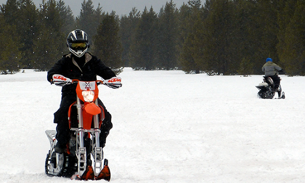 A man in black on a snow bike. 