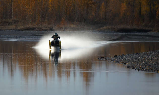 A man riding a snowmobile really fast over open water. 