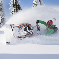 Geoff Kyle in a green snowmobile suit on a Ski-Doo. 