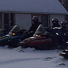 people on sleds near a cabin