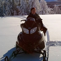 A woman sitting on a black Arctic Cat snowmobile. 
