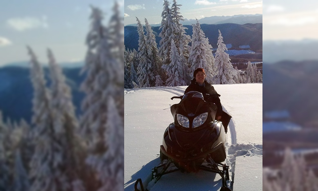 A woman sitting on a black Arctic Cat snowmobile. 