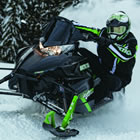 A guy cornering on a black and green sled. 