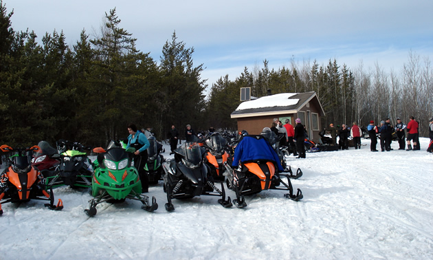 Sledders gathered outside of a cabin. 