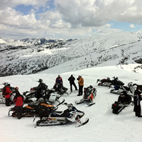 A group of snowmobilers on top of a mountain. 