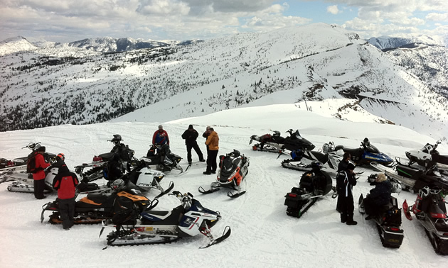 A group of snowmobilers on top of a mountain. 