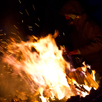 A person siting around a blazing fire. 