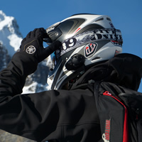 A snowmobiler in a helmet and a backpack and gloves. 