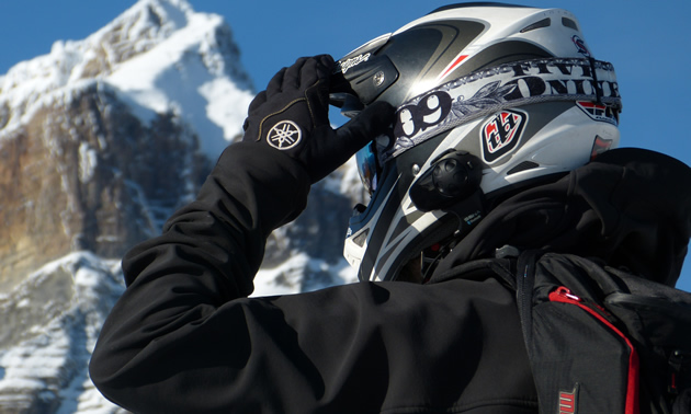 A snowmobiler in a helmet and a backpack and gloves. 