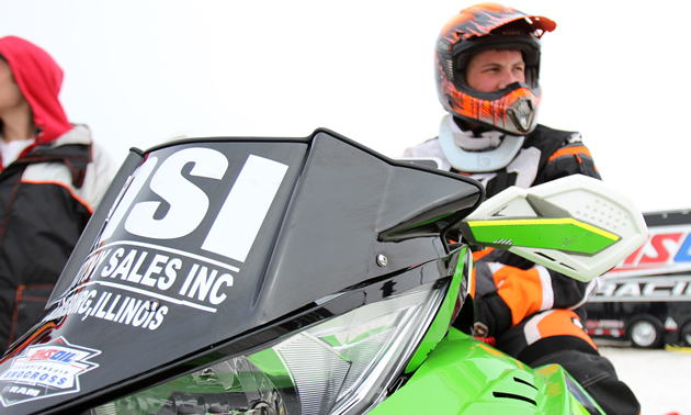 Grant Glashagel snocross racer sitting on his green sled. 