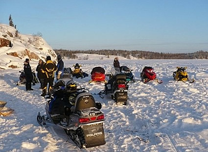 people riding sleds on a trail up north