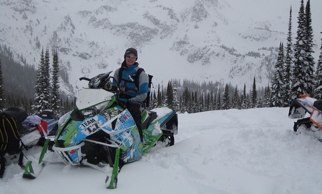 Heather White on a cloudy day.  She is sitting on her parked sled.  