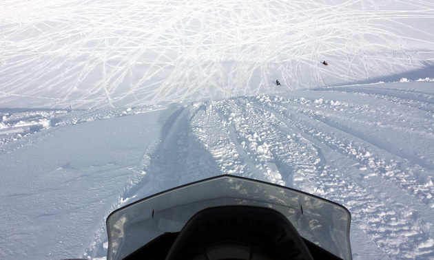 Looking over the handlebars at a steep climb on a snowmobile. 