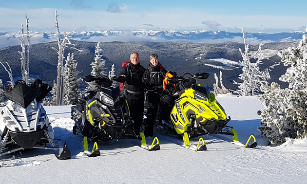A couple posing by their Polaris snowmobiles on Connell Ridge. 