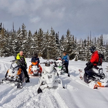 riders getting ready to head out in the snow on sleds