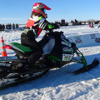 A young woman sitting on a snowmobile at the snow drags. 