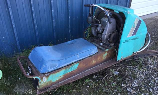 Picture of rusting Johnson snowmobile, showing the seat. The colour is baby blue. 