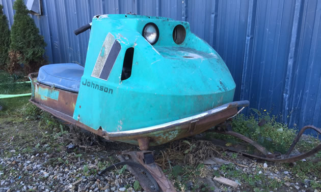 Picture of the front of a rusting Johnson snowmobile. The colour is baby blue. 