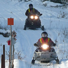 Two sledders about to ride over a bridge. 
