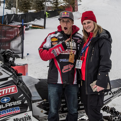 Picture of Julie Benton, standing in front of snowmobile in winter. 