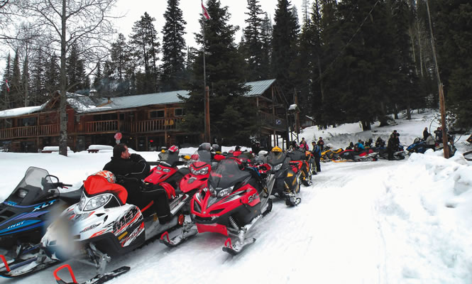 snowmobiles lined up in front of a log building