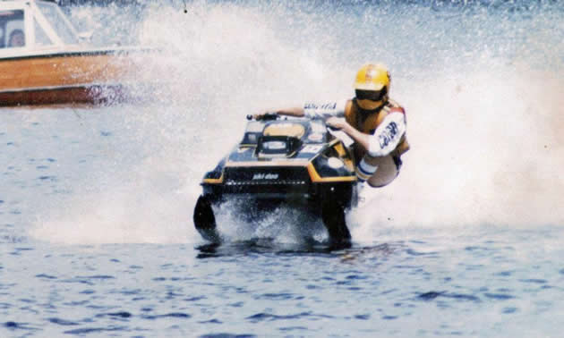 An old photo of Mark Maki racing an old sled on the water. 