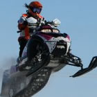 Girl in the air on a snowmobile.